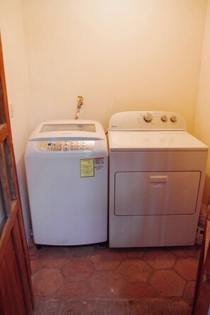 A compact laundry area with a front-loading washer and a top-loading dryer. - Lovely bachelor in Cuenca down-town (Cuenca)
