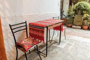 Une chaise avec un coussin à motifs et une table recouverte d’une nappe à rayures.