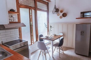 A compact kitchen with a stove, sink, and a dining area with chairs and a table. - Lovely bachelor in Cuenca down-town (Cuenca)