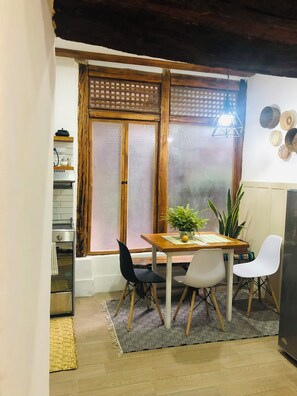 A dining area with a wooden table, two chairs, a potted plant, and a window with a wooden frame. - Lovely bachelor in Cuenca down-town (Cuenca)