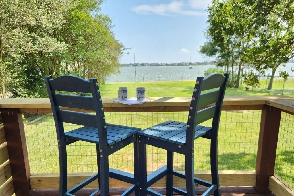 Two chairs facing a table with a view of a lake.