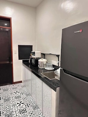 A compact kitchen with a refrigerator, a microwave, a coffee maker, and a toaster.