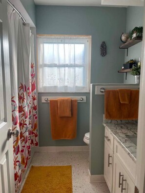 Un baño con ventana, toallero, inodoro y lavamanos.