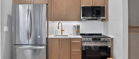 Una cocina moderna con electrodomésticos de acero inoxidable, armarios de madera y un microondas.