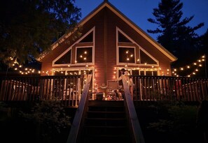 Eine Holzhütte mit einer Treppe, die zu einer Terrasse führt, umgeben von Lichterketten.
