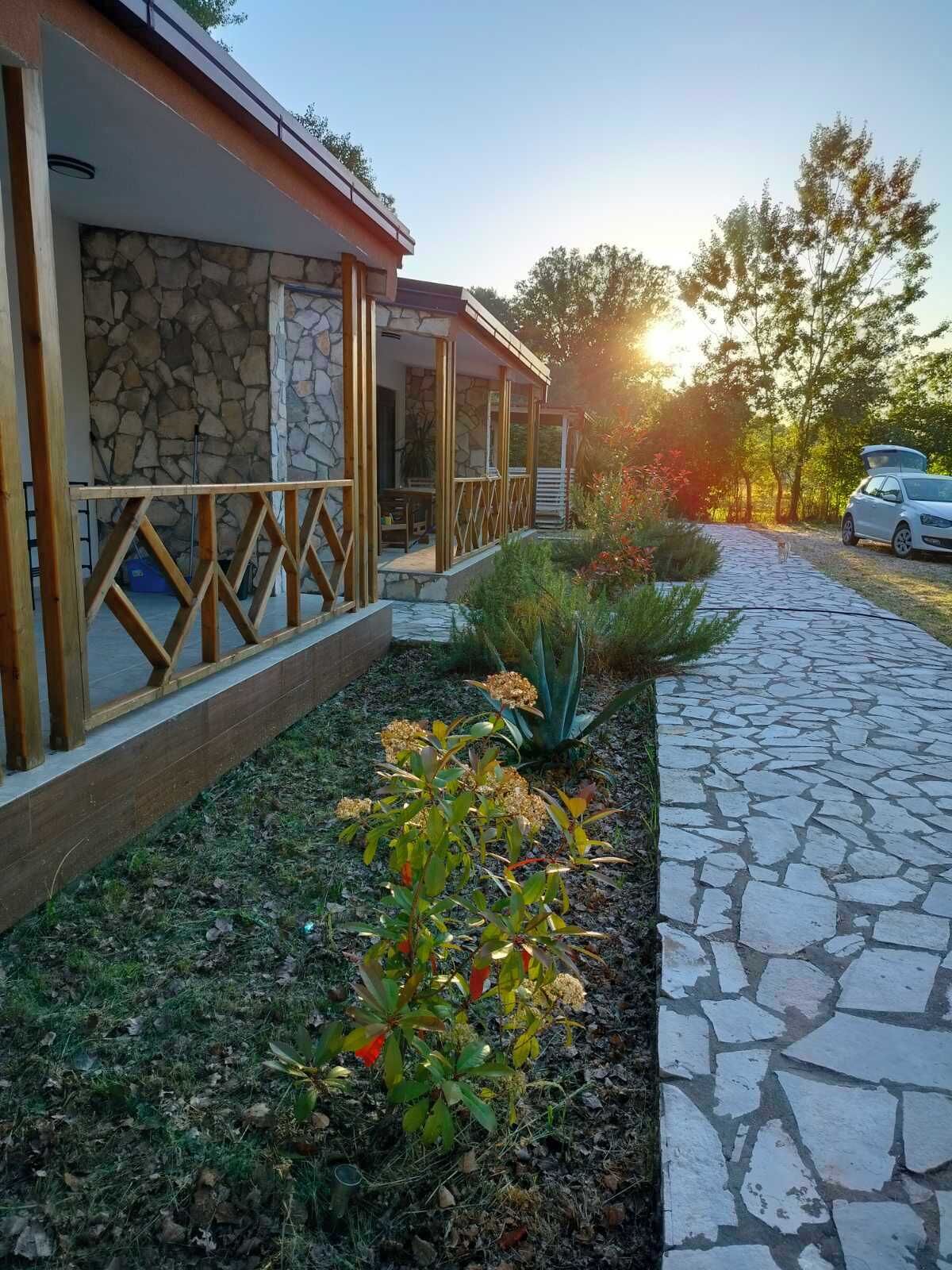 Un sendero de piedra que conduce a un edificio con fachada de piedra y una terraza de madera.