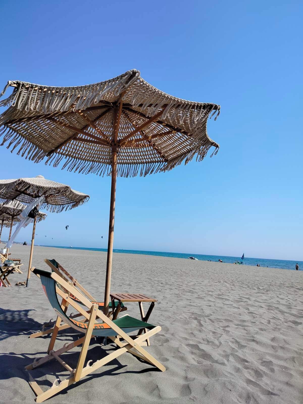 Une plage avec des chaises longues en bois et des parasols en paille.