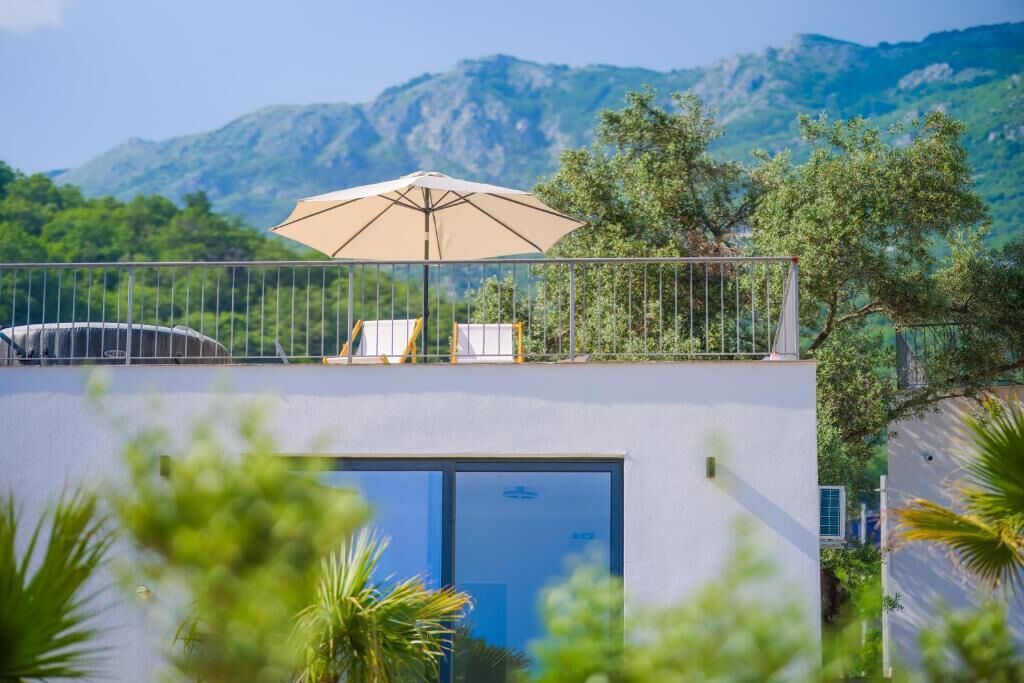 Een balkon met een beige parasol, een stoel en een tafel.