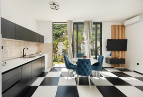 A modern kitchen with a black and white checkered floor, a dining area with blue chairs, and a large window with curtains.