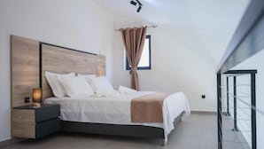 Un dormitori modern amb un llit, una taula de nit i una finestra amb cortines.