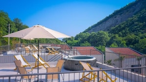 Terraza en la azotea con sillones de sol, una bañera de hidromasaje y vistas a un paisaje montañoso.