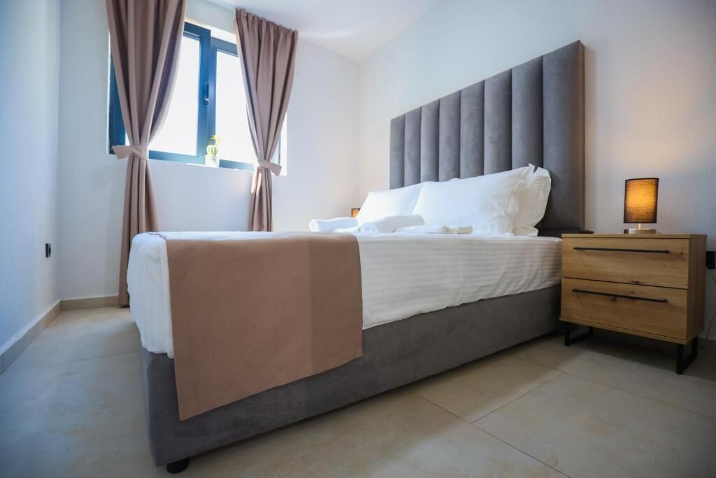 A bedroom with a bed, a bedside table, and curtains.