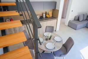 A modern kitchen with a dining area, a staircase, and a grey sofa in a living space. - Rajska Dolina (Boreti)