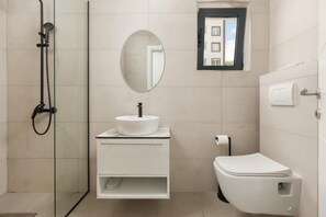 A modern bathroom with a glass-enclosed shower, a white sink with a round mirror, and a toilet. - Rajska Dolina (Boreti)