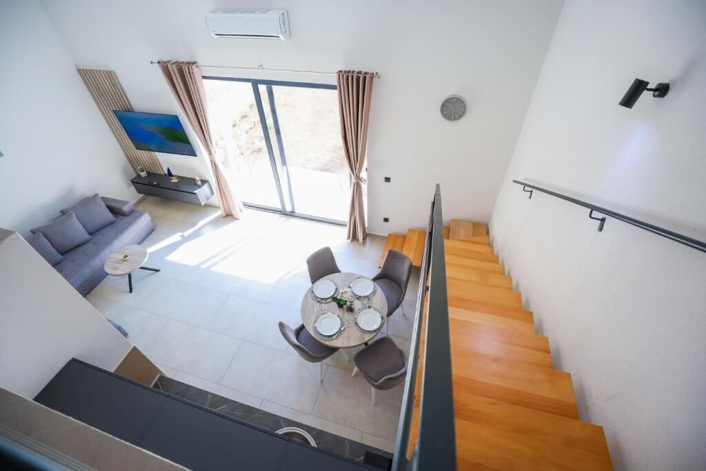 A modern interior with a staircase, a dining area with a round table, and a sofa.
