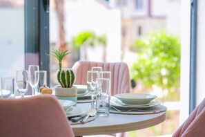 A dining table set with plates, glasses, and cutlery, a cactus plant, and a chair.