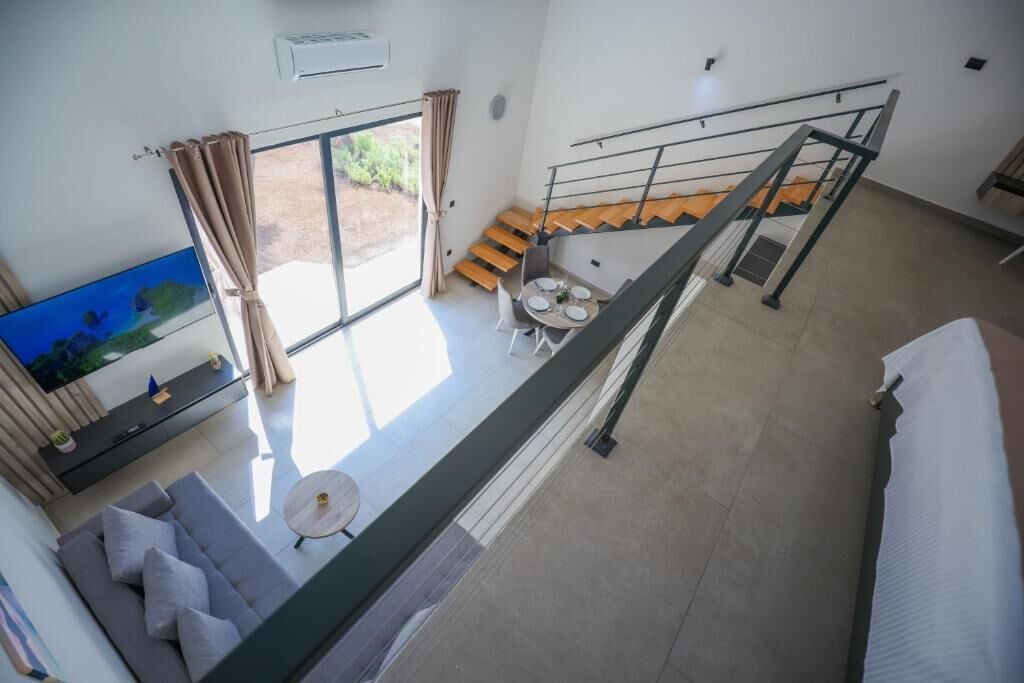 A modern interior with a sofa, a dining table, and a staircase.