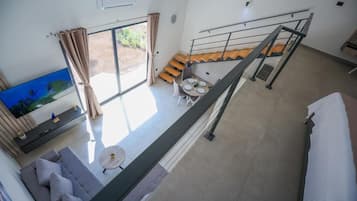 A modern interior with a sofa, a dining table, and a staircase.