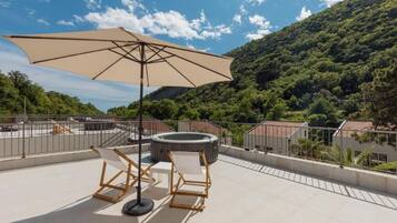 Una terraza en la azotea con un paraguas grande, dos sillones de descanso y un jacuzzi.