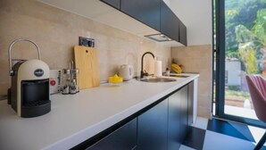 Una cocina moderna con cafetera, tabla de cortar y un lavamanos.