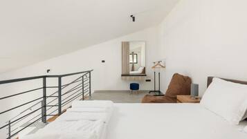 Un dormitorio con cama, mesita de noche, lámpara colgante, espejo y una escalera.