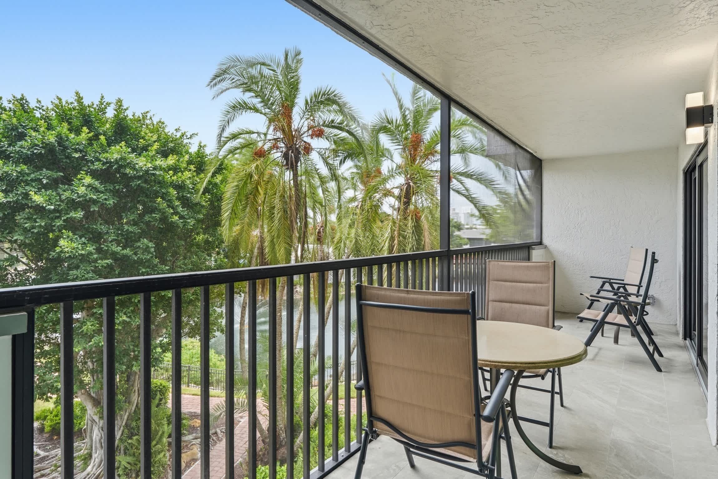 Ein Balkon mit Tisch und Stühlen mit Blick auf einen Garten mit Palmen.