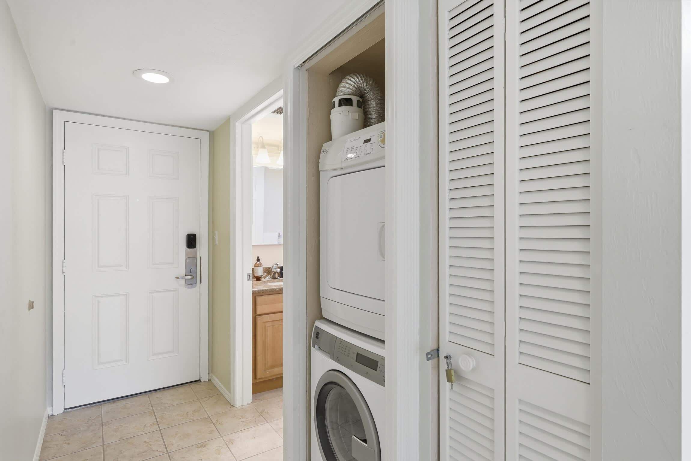 A laundry room with a washing machine and dryer, a door, and a tiled floor.