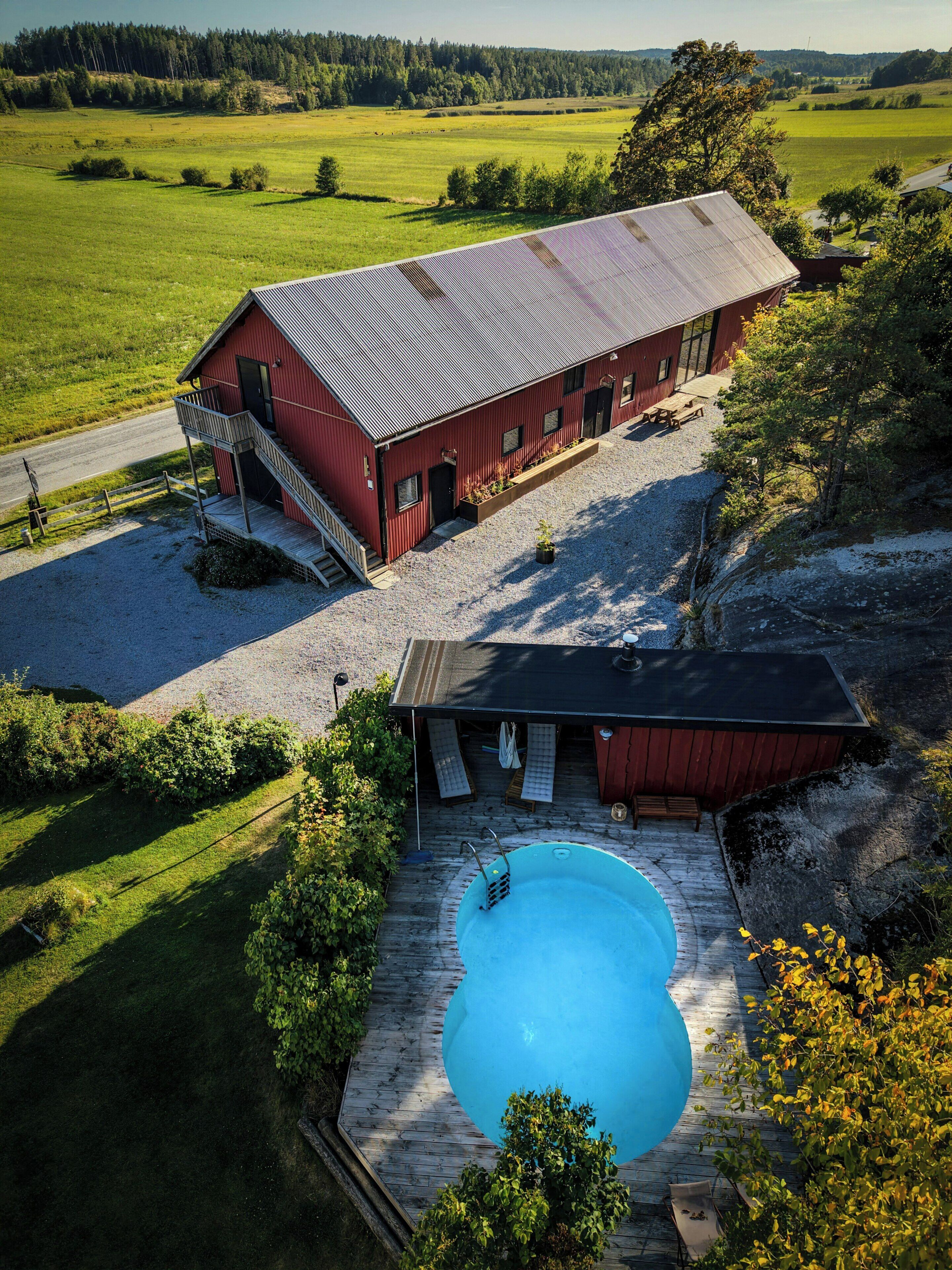 A red barn with a swimming pool and outdoor seating.