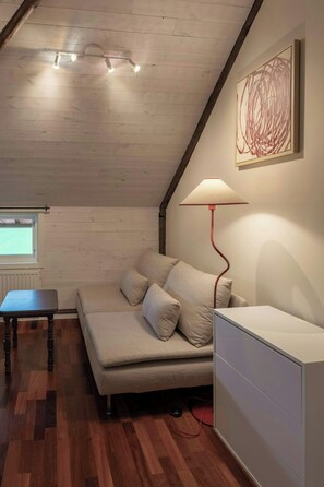 Une pièce chaleureuse avec un plafond en bois, un canapé avec des coussins, une table et une lampe.