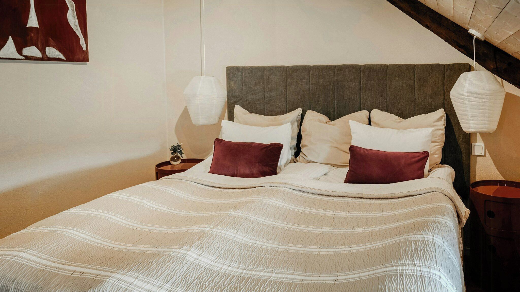 A bed with a striped blanket, a wooden headboard, and two bedside lamps.