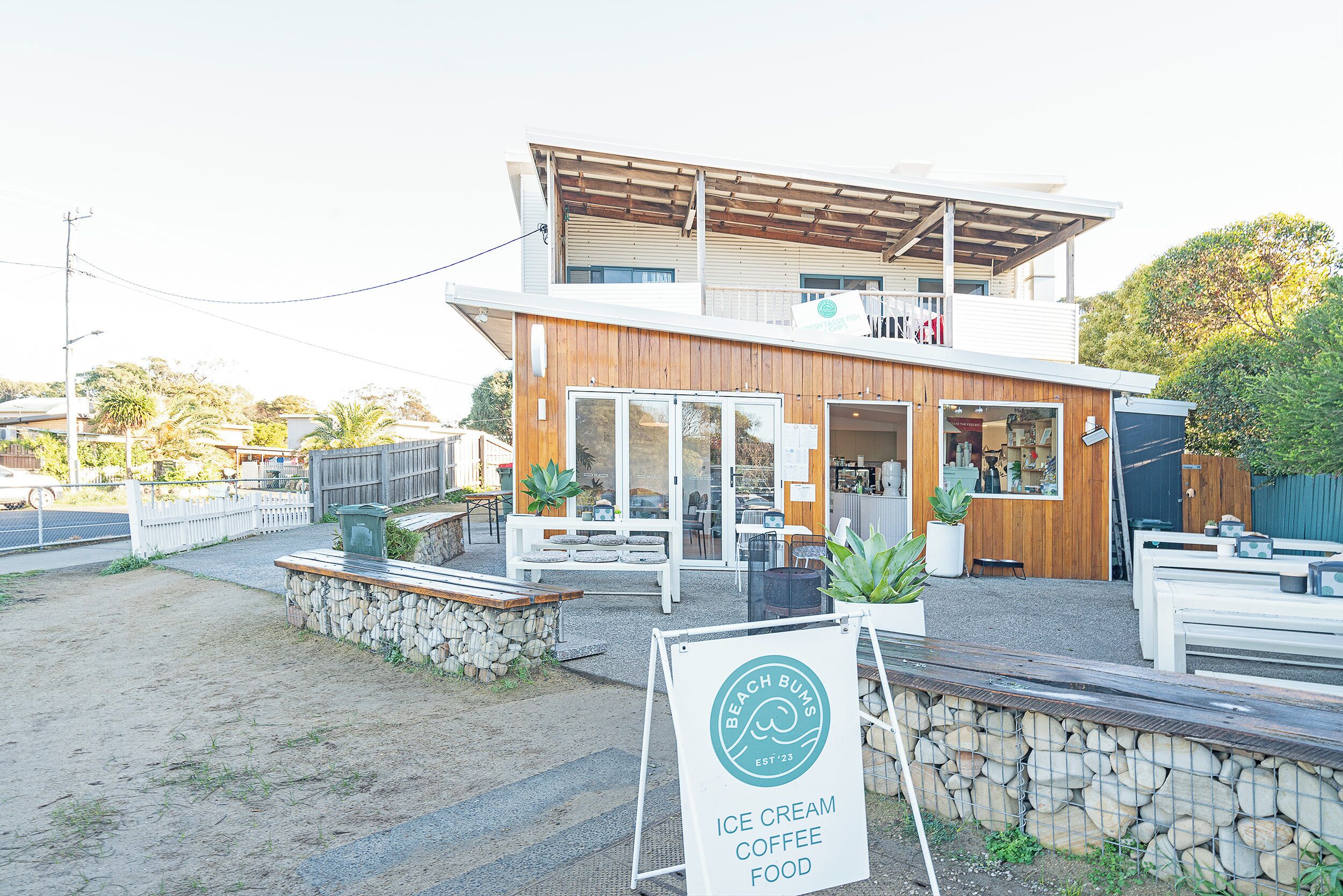 Un bâtiment moderne avec une enseigne indiquant : « Glaces, café et plats à déguster sur la plage ».