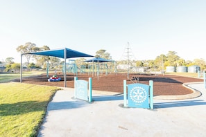 Ein Spielplatz mit einem blauen Baldachin, Spielgeräten und einem Schild, das ihn als Bootsspielplatz kennzeichnet.