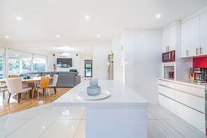 Een moderne keuken met witte kasten, een centraal eiland en een zithoek met een bank en stoelen.