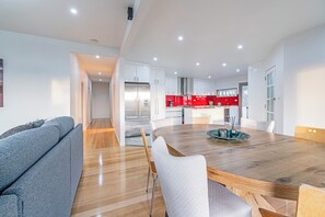 A modern kitchen with white cabinets, a red backsplash, and a stainless steel refrigerator. - Golden Hours Serene Bushland Outlook and Outdoor Spa (Forcett)