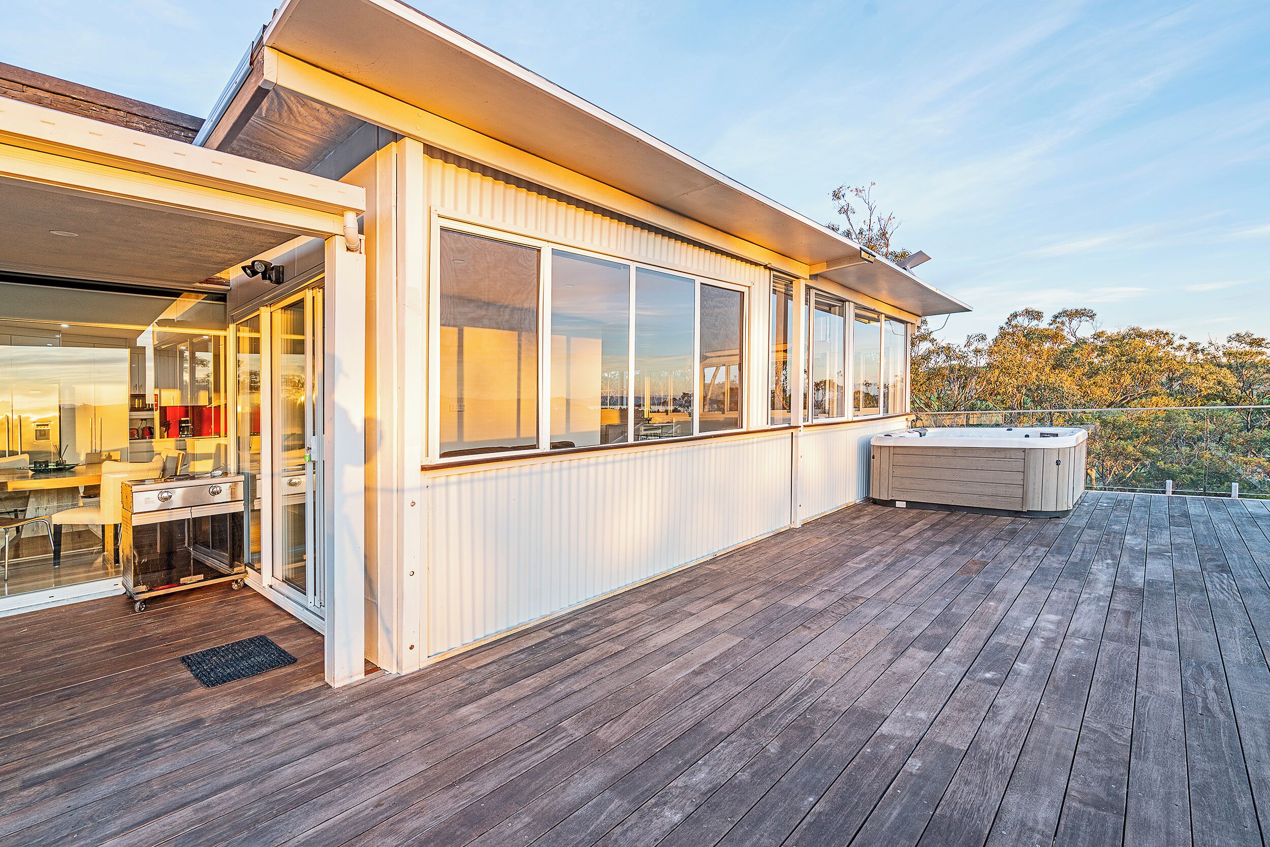 Una casa moderna con terraza, ventanas amplias y un jacuzzi.