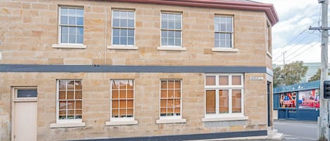 A two-story stone building with multiple windows and a red roof.