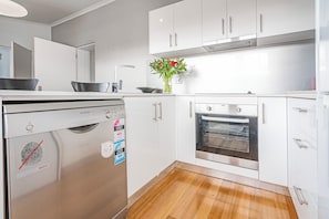 Een moderne keuken met witte kasten, roestvrijstalen apparatuur en een houten vloer.
