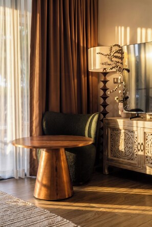 Une pièce comprenant une table ronde en bois, un fauteuil recouvert d’un tissu vert, une lampe décorative et un meuble orné de sculptures complexes.