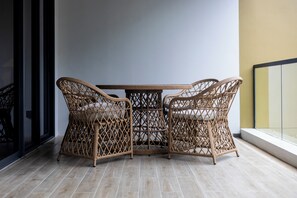 A wicker table with four chairs, a tiled floor, and a window with a view. - NEW! Apartment at Laguna Beachside: 2 bedrooms (Tambon Choeng Thale)