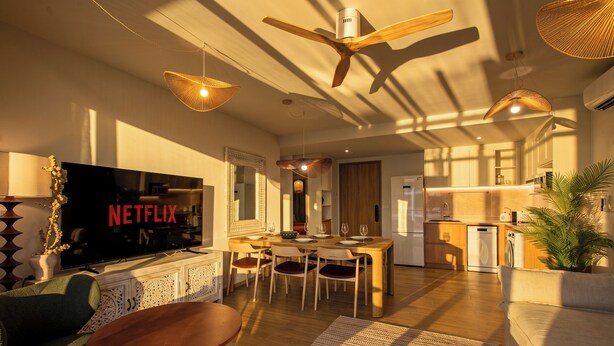 Una sala de estar moderna con un televisor de pantalla plana, muebles de madera y un ventilador de techo.