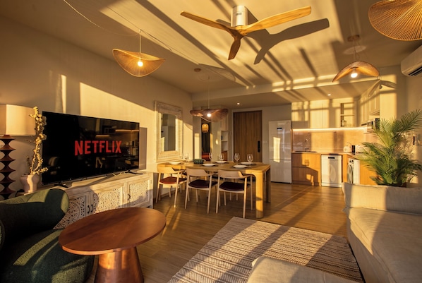 Een moderne woonkamer met een flatscreen televisie, houten meubels en een plafondventilator.