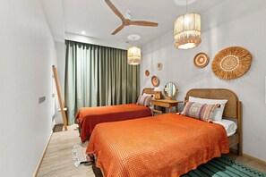 A modern hotel room with two beds, a ceiling fan, and decorative wall art. - NEW! Apartment at Laguna Beachside: 2 bedrooms (Tambon Choeng Thale)