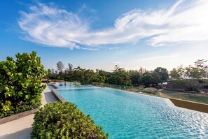 A swimming pool with clear blue water, surrounded by greenery and trees. - NEW! Apartment at Laguna Beachside: 2 bedrooms (Tambon Choeng Thale)