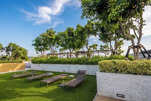 Un jardin sur le toit, doté d’une pelouse artificielle, de chaises longues et d’une structure en forme de pergola.