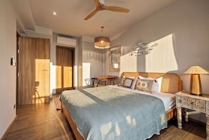 Een slaapkamer met een bed, nachtkastje, lamp en een plafondventilator.