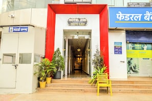 The entrance to Hotel JHD with a red facade, a reception desk, and potted plants. - Hotel JHD Luxury Stay Restro & Sky Bar (Udaipur)