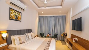 A hotel room with a bed, a desk, a chair, a television, and a window with curtains. - Hotel JHD Luxury Stay Restro & Sky Bar (Udaipur)