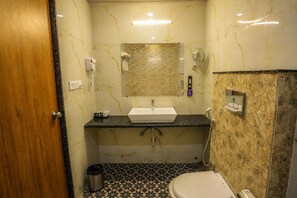A bathroom with a marble sink, a toilet, a shower, and a trash can. - Hotel JHD Luxury Stay Restro & Sky Bar (Udaipur)