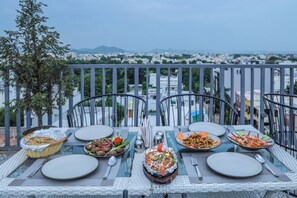 A table set for a meal with a city view in the background. - Hotel JHD Luxury Stay Restro & Sky Bar (Udaipur)