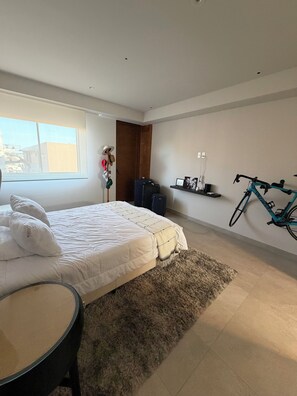 Een slaapkamer met een bed, een stoel, een fiets en een raam.